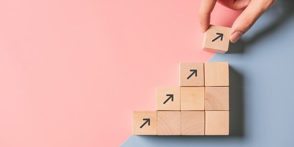 Business concept growth success process, Close up man hand arranging wood block stacking as step stair on paper blue and pink background, copy space.