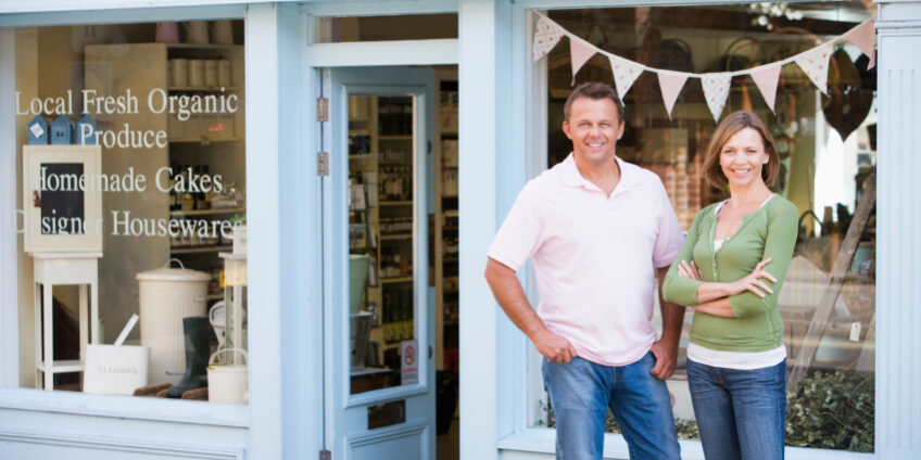 Couple standing in front of organic food store smiling