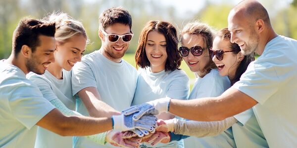 group of volunteers putting hands on top in park